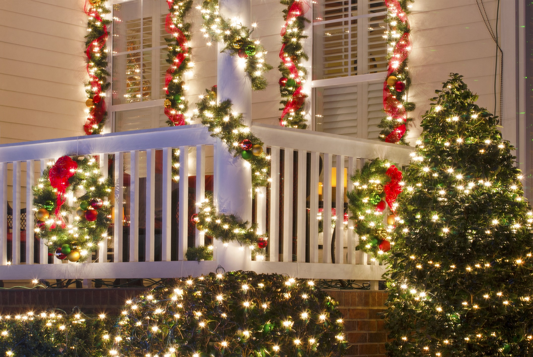 Festively decorated porch with garlands and lights, creating a warm holiday atmosphere. Wreaths and red ribbons enhance the seasonal charm.